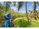 Lush backyard with mature landscaping featuring kayaks, play equipment, and waterfront access at 1720 Mariner Way, Tarpon Springs, FL 34689