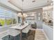 Bright dining room with modern chandelier, gray walls, built-in shelving, and a large window overlooking lush greenery at 1720 Mariner Way, Tarpon Springs, FL 34689