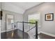 Upstairs hallway featuring dark wood floors, neutral paint, and a window with natural light overlooking trees and greenery at 1720 Mariner Way, Tarpon Springs, FL 34689