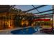 Twilight view of the enclosed pool with lounge chairs and tropical landscape at 1720 Mariner Way, Tarpon Springs, FL 34689