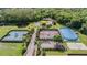 Aerial view of community tennis and sports courts surrounded by lush greenery and serene pond at 17927 Bahama Isle Cir, Tampa, FL 33647