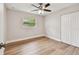 Light-filled bedroom features wood-look floors, ceiling fan, and ample natural light at 1870 Wateroak W Dr, Clearwater, FL 33764