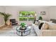 Cozy living room featuring a comfortable sofa, area rug, and a view of the lush greenery outside at 1870 Wateroak W Dr, Clearwater, FL 33764