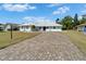 Inviting single-story home featuring a well-manicured lawn and brick paver driveway at 1929 New Bedford Dr, Sun City Center, FL 33573