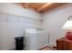 Functional laundry room featuring a washer and dryer, accented with patterned wallpaper and a wooden ceiling at 20926 Ragan Ln, Land O Lakes, FL 34638