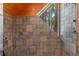 Tiled shower with a window offering a view of the outdoors, complemented by a wood-paneled ceiling at 20926 Ragan Ln, Land O Lakes, FL 34638