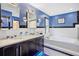 Bright bathroom featuring blue accent walls, dual sinks, and a luxurious soaking tub at 2217 Brevard Ne Rd, St Petersburg, FL 33704