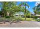 Inviting two-story home with a lush front yard, mature tree, and a charming light-green exterior at 2217 Brevard Ne Rd, St Petersburg, FL 33704