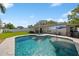 Backyard pool with travertine tile, sun umbrella, fountain features, and grassy yard and white picket fence at 2648 Countryclub Dr, Clearwater, FL 33761