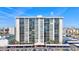 High-rise building with multiple balconies and a parking lot, set against a blue sky at 400 Island Way # 1708, Clearwater Beach, FL 33767