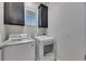 Well-lit laundry room with modern washer and dryer units, and overhead cabinets at 5236 Wishing Arch Dr, Apollo Beach, FL 33572