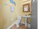 Bright half bathroom with a pedestal sink, toilet, and square decorative mirror at 6103 Saint Remy Way, Lutz, FL 33558