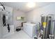 Laundry room with washer, dryer, shelving, and a hot water heater at 6712 W Clifton St, Tampa, FL 33634