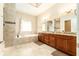 A primary bathroom showing double sinks, a soaking tub, granite counters, and tiled floors at 819 Birdie Way, Apollo Beach, FL 33572