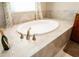 Oval bathtub with brushed metal fixtures surrounded by neutral tile at 819 Birdie Way, Apollo Beach, FL 33572