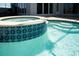 Close-up of hot tub with tiled trim and waterfall feature flowing into the pool, offering a relaxing escape at 819 Birdie Way, Apollo Beach, FL 33572