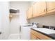 Bright laundry room with washer, dryer, sink, and wood cabinets at 819 Birdie Way, Apollo Beach, FL 33572