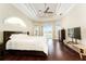 A primary bedroom featuring a tray ceiling, hardwood floors, and sliding glass doors to the pool at 819 Birdie Way, Apollo Beach, FL 33572