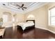 Spacious primary bedroom with tray ceiling, hardwood floors, and an arched window for natural light at 819 Birdie Way, Apollo Beach, FL 33572