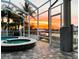 A luxurious in-ground pool and jacuzzi are on an outdoor patio, offering tranquil water views and a picturesque sunset at 819 Birdie Way, Apollo Beach, FL 33572