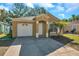 Inviting single-story home with an attached garage, an arched doorway, and a well-maintained lawn at 8528 Quarter Horse Dr, Riverview, FL 33578