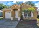 Charming single-story home with tan stucco, an arched doorway, and neat landscaping in a sunny setting at 8528 Quarter Horse Dr, Riverview, FL 33578