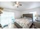 Bedroom features a ceiling fan, wood-look floors, and a sliding glass door leading to a patio at 8528 Quarter Horse Dr, Riverview, FL 33578