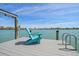 Inviting dock featuring a relaxing blue chair and access ladder, perfect for enjoying waterfront views on a sunny day at 8685 E Bay Dr, Treasure Island, FL 33706