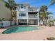 Gorgeous coastal home with multiple balconies, a private pool, and a brick patio for outdoor relaxation at 8685 E Bay Dr, Treasure Island, FL 33706