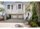 Stunning raised home with lush landscaping, garage, and inviting stairway to the front door at 8685 E Bay Dr, Treasure Island, FL 33706