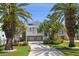 Charming coastal home on stilts featuring a spacious driveway, lush landscaping, and a welcoming facade at 8685 E Bay Dr, Treasure Island, FL 33706