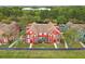 Aerial view of vibrant red townhomes with well-maintained lawns and lush landscaping on a sunny day at 9118 Lake Chase Island Way # 9118, Tampa, FL 33626