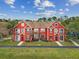 A bright red townhouse with balconies, complemented by green lawn and lush landscaping under blue skies at 9118 Lake Chase Island Way # 9118, Tampa, FL 33626