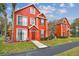 Inviting red two-story townhome featuring a well-manicured lawn and tasteful landscaping, creating a welcoming entrance at 9118 Lake Chase Island Way # 9118, Tampa, FL 33626