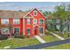 Red townhouse with front yard features, mature tree, and a welcoming entryway with blue sky background at 9118 Lake Chase Island Way # 9118, Tampa, FL 33626