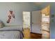 Light blue bedroom with hardwood floors, giraffe art, and doorways leading to the bathroom and office at 103 Morgan Dr, Belleair Beach, FL 33786