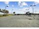 Outdoor tennis court featuring well-maintained surface, net, perimeter fencing, and lighting with ample space for recreational play at 1030 Tidewater Shores Loop # 104, Bradenton, FL 34208