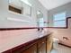 Bathroom with tile countertop, pink sink, vintage-style cabinets and a window at 10754 63Rd Ave, Seminole, FL 33772