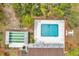 Aerial view of a community pool and shuffleboard court surrounded by lush green landscaping and mature trees at 13102 Wagner Dr, Hudson, FL 34667