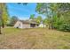 Exterior view of home featuring mature trees, spacious yard, and a screened-in patio at 13102 Wagner Dr, Hudson, FL 34667
