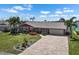 Charming home boasts a lush lawn, colorful landscaping, and an inviting brick driveway at 1804 Bunker Hill Dr, Sun City Center, FL 33573