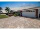 Beautiful home with paved driveway, attached garage, colorful landscaping, and a mature palm tree at 1804 Bunker Hill Dr, Sun City Center, FL 33573