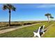 Relaxing view of a bench with a sidewalk near the beach and palm trees at 2055 Gulf Of Mexico Dr # G2-213, Longboat Key, FL 34228