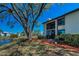 Exterior view of condo with a screened-in lanai overlooking the lake, complemented by mature trees and landscaping at 232 Nina Way # 232, Oldsmar, FL 34677