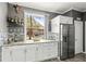 Bright kitchen featuring white cabinets, stainless steel refrigerator, and a view to the front yard at 2759 Conch Hollow Dr, Brandon, FL 33511