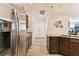 View of stainless steel refrigerator and granite countertops, with a hallway featuring a modern decorative clock in background at 32853 Woodthrush Way, Wesley Chapel, FL 33545