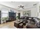 Inviting living room featuring a comfortable leather sofa, a ceiling fan, and large windows, creating a bright and airy space at 32853 Woodthrush Way, Wesley Chapel, FL 33545