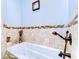 Bright bathroom featuring a tiled-in tub with jacuzzi jets and mosaic tile border at 37410 Dixie Ave, Dade City, FL 33525