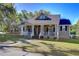 Inviting home featuring a classic front porch, showcasing a well-kept lawn and mature trees on a sunny day at 37410 Dixie Ave, Dade City, FL 33525