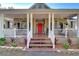 Inviting front porch with a vibrant red door, adorned with hanging plants and welcoming decor at 37410 Dixie Ave, Dade City, FL 33525